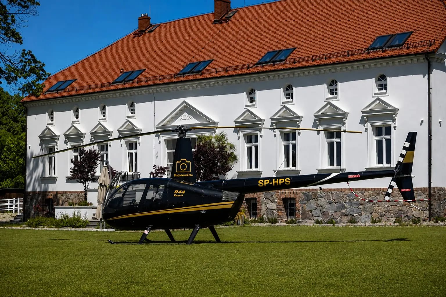 Boczny profil Robinsona R44 na tle obiektu weselnego